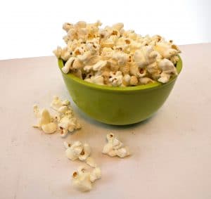 popcorn in a green bowl on a white table