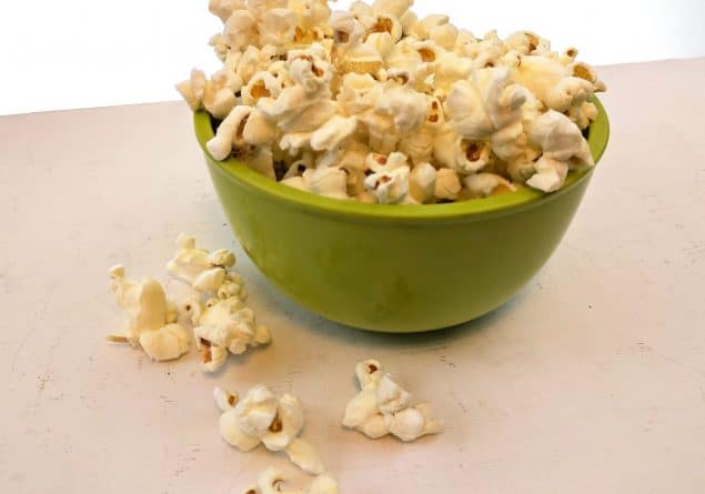 popcorn in a green bowl on a white table